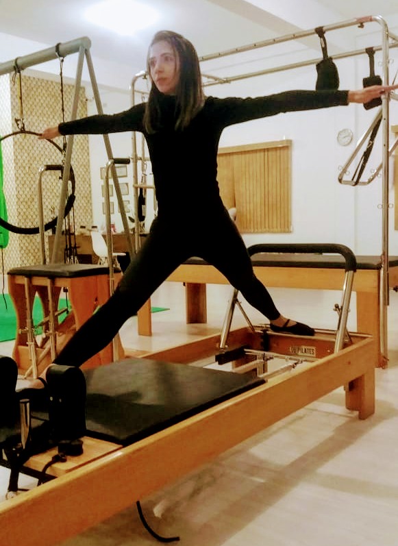 Aluna praticando pilates no aparelho